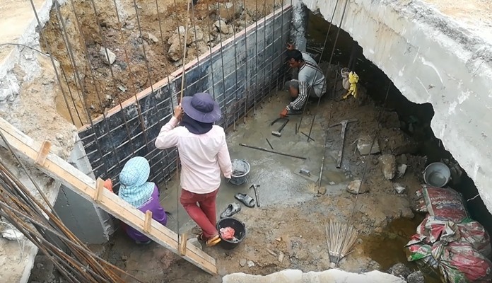 Nongprue workers build a spillway to drain floodwaters from Tropical Village into sub-district drains.