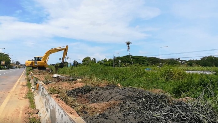 Pattaya engineers use a backhoe to dredge a new canal on the railway-parallel road to allow floodwaters to flow to waterways leading to the sea.