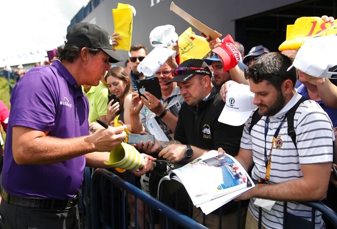 Phil Mickelson of the United States signs autographs on the 18th fairway during a practice round ahead of the start of the British Open golf championships at Royal Portrush in Northern Ireland, Tuesday, July 16, 2019. The British Open starts Thursday. (AP Photo/Peter Morrison)