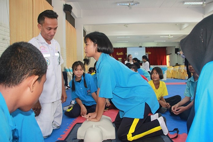 A student is in full concentration as she performs CPR on a training mannequin.