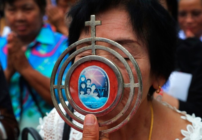 Catholic devotee kisses a sacramental with an image of the seven martyrs at cemetery during the 30th anniversary of the beatification of seven martyrs at Songkhon in Mukdahan province, northeastern of Thailand Saturday, Oct. 19, 2019. (AP Photo/Sakchai Lalit)