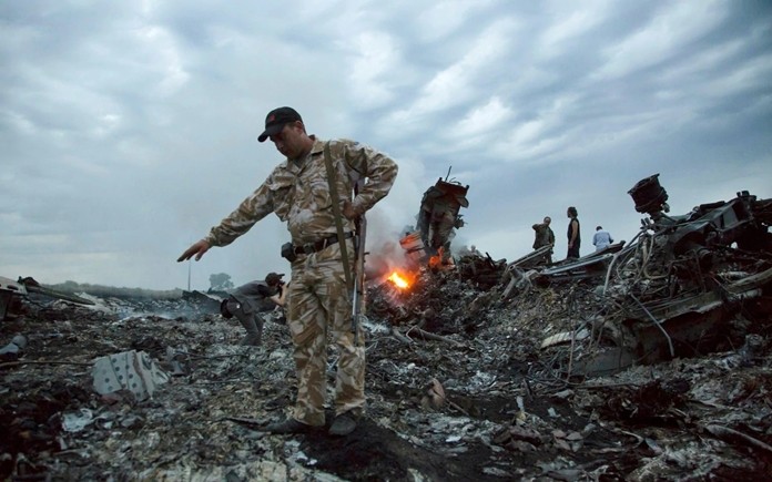 In this July 17, 2014. file photo, people walk amongst the debris at the crash site of MH17 passenger plane near the village of Grabovo, Ukraine, that left 298 people killed. (AP Photo/Dmitry Lovetsky, File)