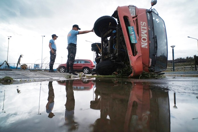 Police inspect a truck that was damaged as Typhoon Kammuri slammed Legazpi city, Albay province, southeast of Manila, Philippines, Tuesday, Dec. 3, 2019. (AP Photo)