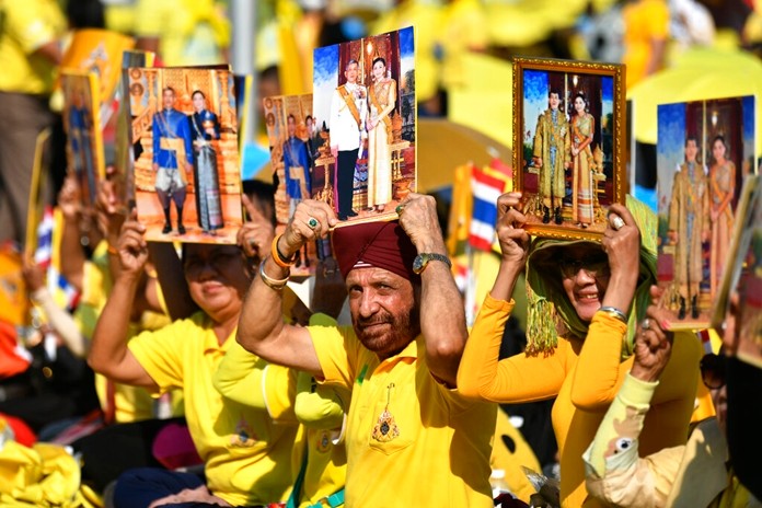 Well-wishers hold the portraits of HM King Maha Vajiralongkorn and HM Queen Suthida outside the Grand Palace in Bangkok, Thailand, Thursday, Dec. 12, 2019. (AP Photo/Suganya Samnangjam)