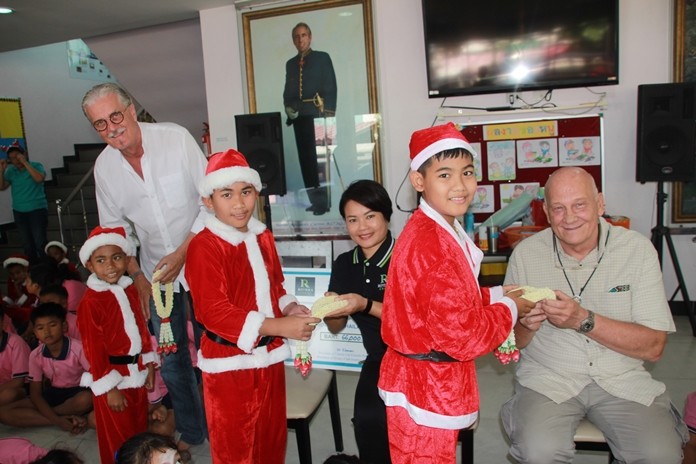 Classic Cars Club President Jo Klemm, Uboljit Thumchob, marketing manager for the Rivera Group, and Jan Abbink of Rotary District 3340 receive thank you garlands from an appreciative group of children.
