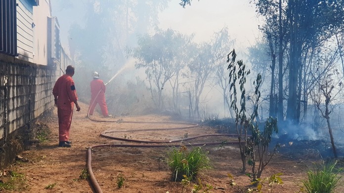 Firefighters arrived in time as the brush roared too close to homes in Sattahip’s Rungroj Village 7.