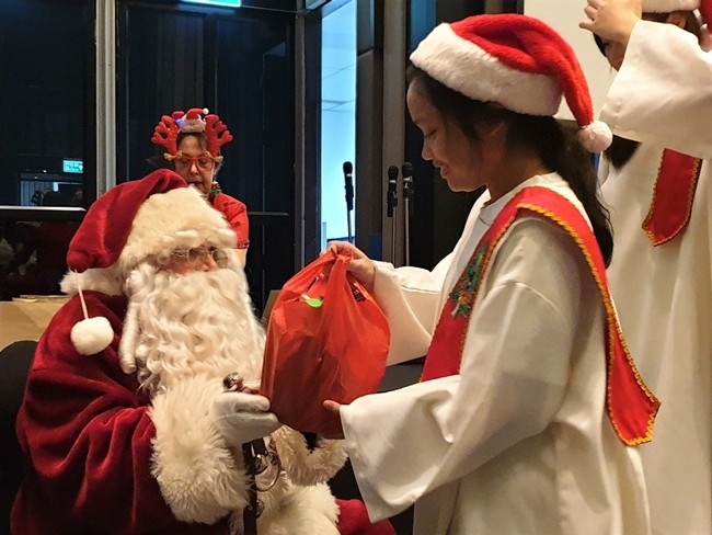 Oh, it is so heavy, this young lady seems to be thinking as she accepts her present from Santa.