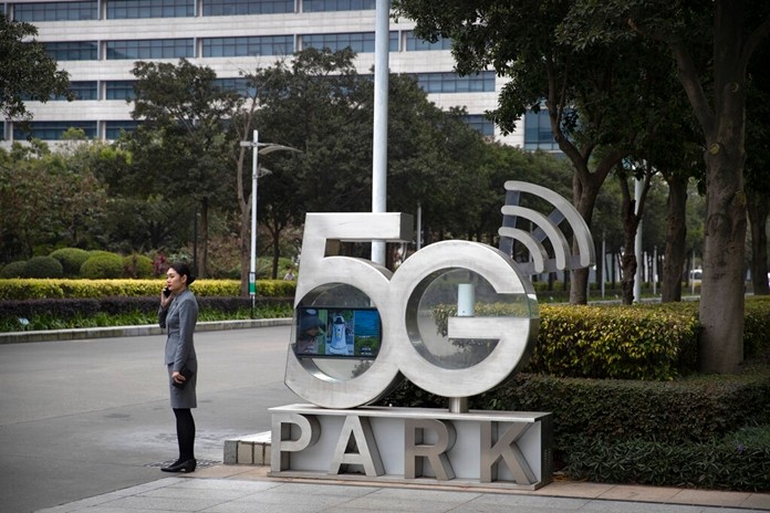 A Huawei employee talks on her cellphone as she stands next to a sign at Huawei's campus in Shenzhen in southern China's Guandong Province, Thursday, Dec. 5, 2019. (AP Photo/Mark Schiefelbein)