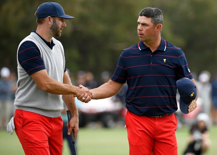 U.S. team player Dustin Johnson, left, and playing partner Gary Woodland shake hands after winning in their foursome match. (AP Photo/Andy Brownbill)