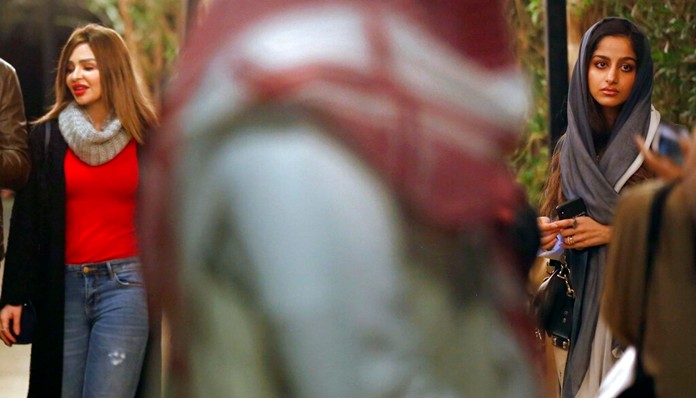 In this Dec. 13, 2019 photo, a man walks by women visiting the Diriyah Oasis amusement park in Diriyah on the outskirts of Riyadh, Saudi Arabia. (AP Photo/Amr Nabil)