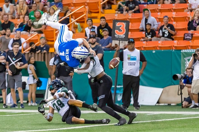 BYU quarterback Zach Wilson (1) loses the football on a hit by Hawaii defensive back Eugene Ford, right, as Wilson tried to leap into the end zone during the second half of the Hawaii Bowl NCAA college football game Tuesday, Dec. 24, 2019, in Honolulu. Hawaii recovered the football in the end zone for a touchback. (AP Photo/Eugene Tanner)