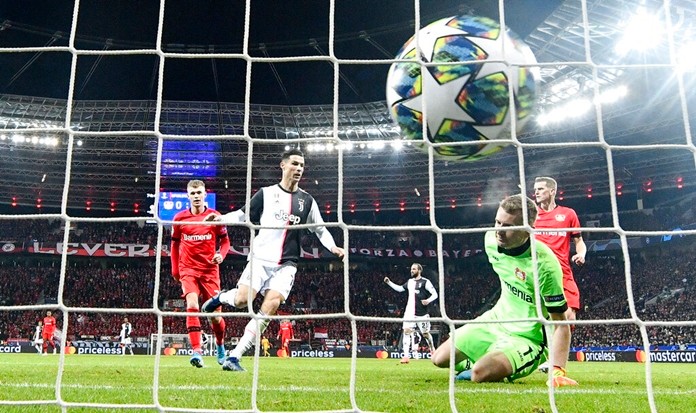 Juventus' Cristiano Ronaldo, center, scores the opening goal against Leverkusen's goalkeeper Lukas Hradecky during the Champions League Group D soccer match between Bayer Leverkusen and Juventus at the Bay Arena in Leverkusen, Germany, Wednesday, Dec. 11, 2019. (AP Photo/Martin Meissner)