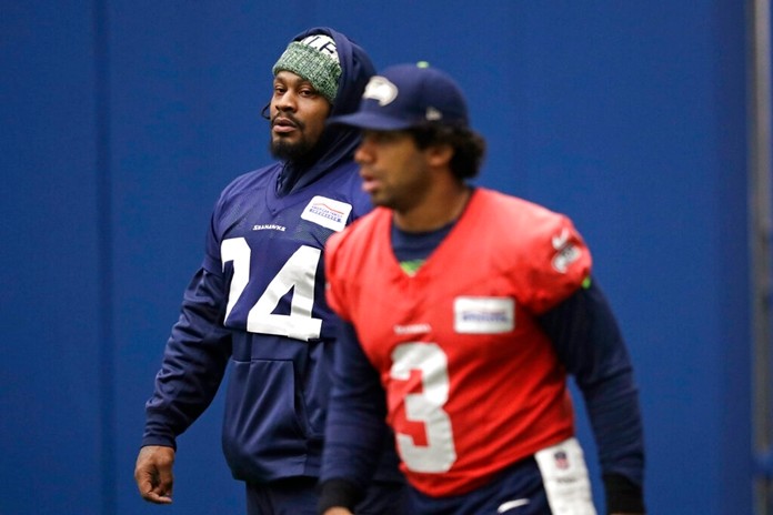 Seattle Seahawks running back Marshawn Lynch, left, looks across at quarterback Russell Wilson during warmups at the NFL football team's practice facility Tuesday, Dec. 24, 2019, in Renton, Wash. When Lynch played his last game for the Seahawks in 2016, the idea of him ever wearing a Seahawks uniform again seemed preposterous. Yet, here are the Seahawks getting ready to have Lynch potentially play a major role Sunday against San Francisco with the NFC West title on the line. (AP Photo/Elaine Thompson)
