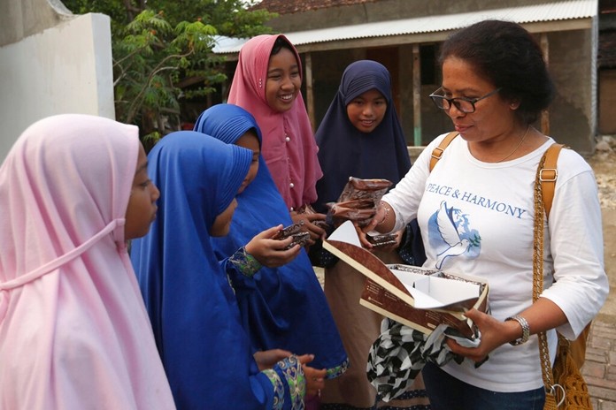 Ni LuhErniati, right, gives cakes to Ali Fauzi's daughter and relatives while visiting Fauzi's home in Tenggulun, East Java, Indonesia, on Saturday, April 27, 2019. (AP Photo/TatanSyuflana)