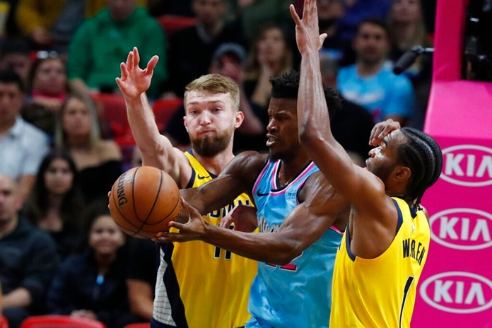 Miami Heat forward Jimmy Butler, center, loses control of the ball as he is guarded by Indiana Pacers forwards Domantas Sabonis, left, and T.J. Warren during the first half of an NBA basketball game Friday, Dec. 27, 2019, in Miami. (AP Photo/Wilfredo Lee)