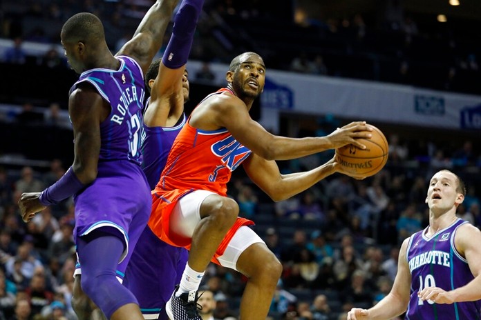 Oklahoma City Thunder's Chris Paul (3) looks for the basket as he flies by Charlotte Hornets' Terry Rozier (3) and P.J. Washington (25) during the second half of an NBA basketball game in Charlotte, N.C., Friday, Dec. 27, 2019. The Thunder won in overtime, 104-102. (AP Photo/Bob Leverone)