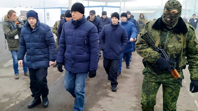 A Russia-backed separatist soldier escorts a group of separatists war prisoners after they were exchanged near the checkpoint Horlivka, eastern Ukraine, Sunday, Dec. 29, 2019. (AP Photo/Alexei Alexandrov)