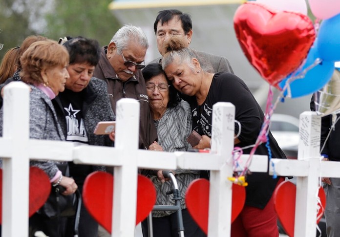 In this Nov. 10, 2017, file photo, family and friends gather around a makeshift memorial for the victims of the First Baptist Church shooting at Sutherland Springs Baptist Church in Sutherland Springs, Texas. (AP Photo/Eric Gay, File)