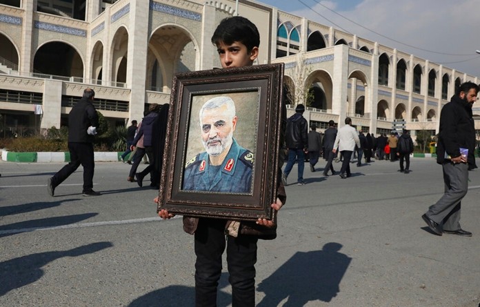 A boy carries a portrait of Iranian Revolutionary Guard Gen. Qassem Soleimani, who was killed in the U.S. airstrike in Iraq, prior to the Friday prayers in Tehran, Iran, Jan. 3, 2020. (AP Photo/Vahid Salemi)