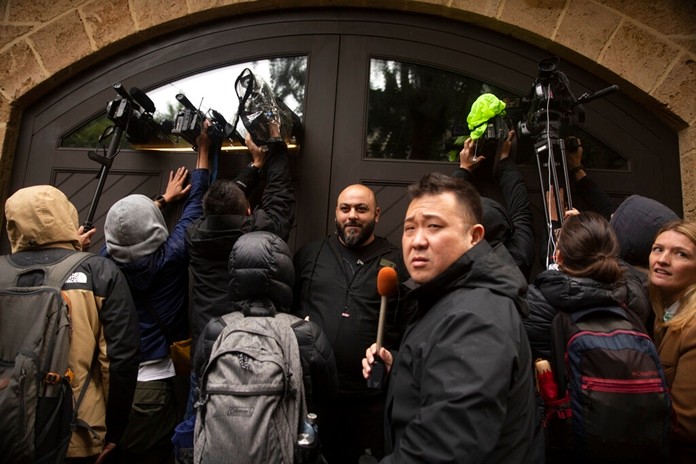 A private security guard, center, stands as journalists film through the garage window of the home of former Nissan Chairman Carlos Ghosn in Beirut, Lebanon, Thursday, Jan. 2, 2020.(AP Photo/Maya Alleruzzo)