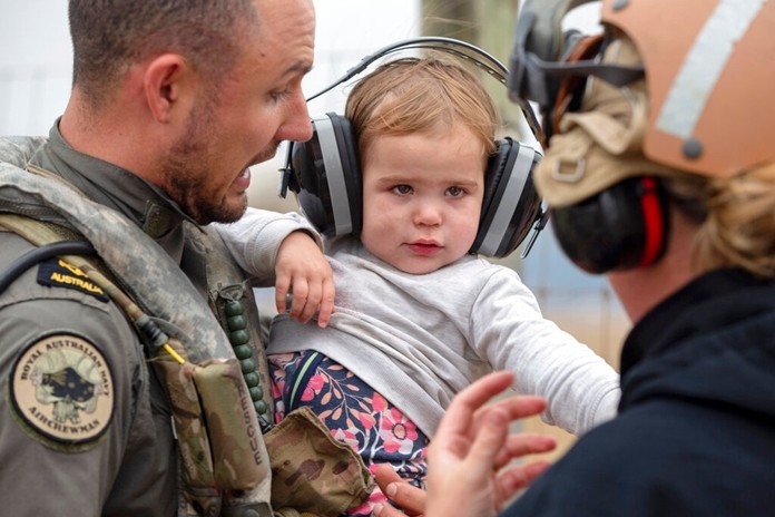 A child is helped onto a helicopter as the fire ravaged community of Mallacoota is evacuated, Sunday, Jan. 5, 2020. The wildfires have so far scorched an area twice the size of the U.S. state of Maryland. (Corporal Nicole Dorrett/ADF via AP)