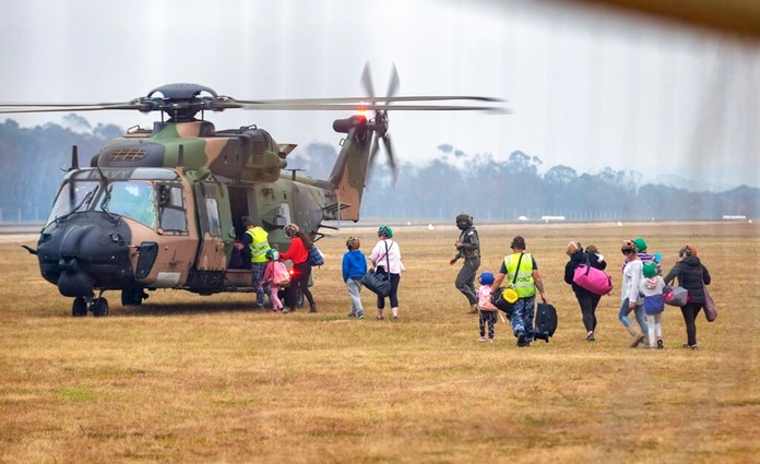 People walk to board a helicopter as the fire ravaged community of Mallacoota is evacuated, Sunday, Jan. 5, 2020. The wildfires have so far scorched an area twice the size of the U.S. state of Maryland. (Corporal Nicole Dorrett/ADF via AP)