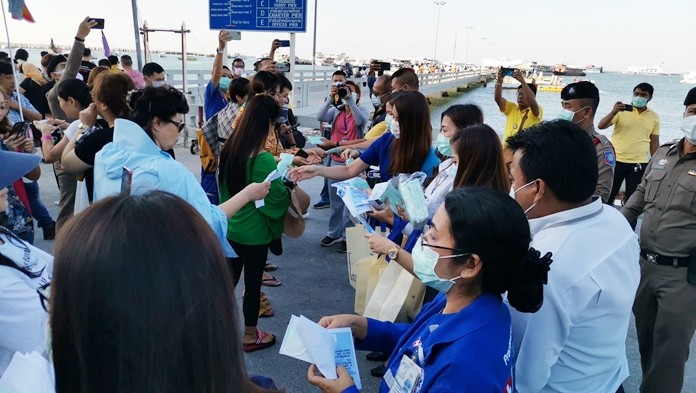 Police officers and volunteers distribute face masks to people at Bali Hai pier.