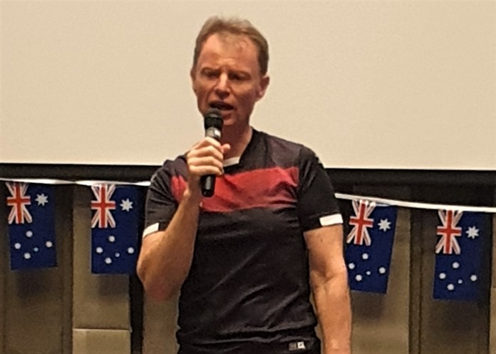 MC Ren Lexander, with several Australian flags behind him, reminds his PCEC audience that it is Australia Day.