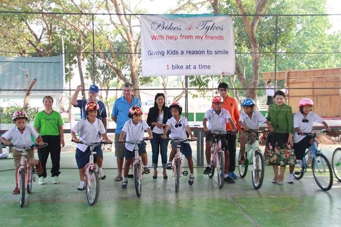 Pattaya Sports Club Welfare Chairwoman Noy Emerson and Bikes 4 Tykes program founder Rick Bevington present the last of the 30 bicycles to smiling youths at Wat Nongket Noi School.