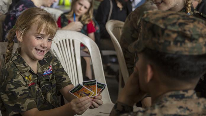 U.S. Marine Lance Cpl. Yaxel Santiago Rodriguez plays cards with an evacuee during processing at a simulated noncombatant evacuation operation as part of exercise Cobra Gold 2020 at U-Tapao Airfield, Rayong. (U.S. Marine Corps photo by Staff Sgt. Jordan E. Gilbert)