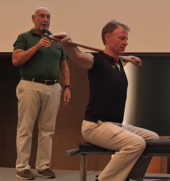 David Shnider guides PCEC Member Ren Lexander in performing an exercise of his neck muscles before they proceeded on to demonstrate other beneficial exercises.