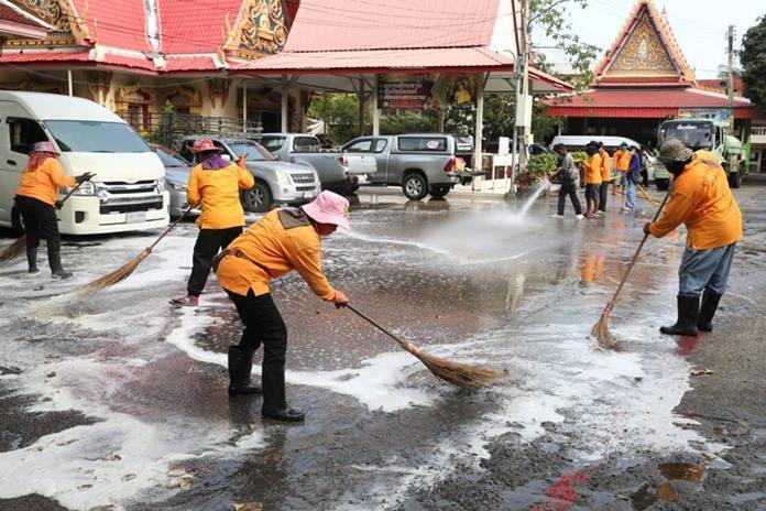 Public health workers scrub down the outside of Wat Thamsamakee.