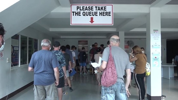 Foreigners are seen in a long queue waiting to submit 30-day visa extension requirement at the Immigration temporary center.