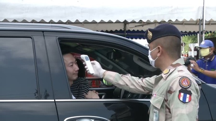 An official at checkpoint observe a traveler’s temperature as part of CCOVID-19 screening.