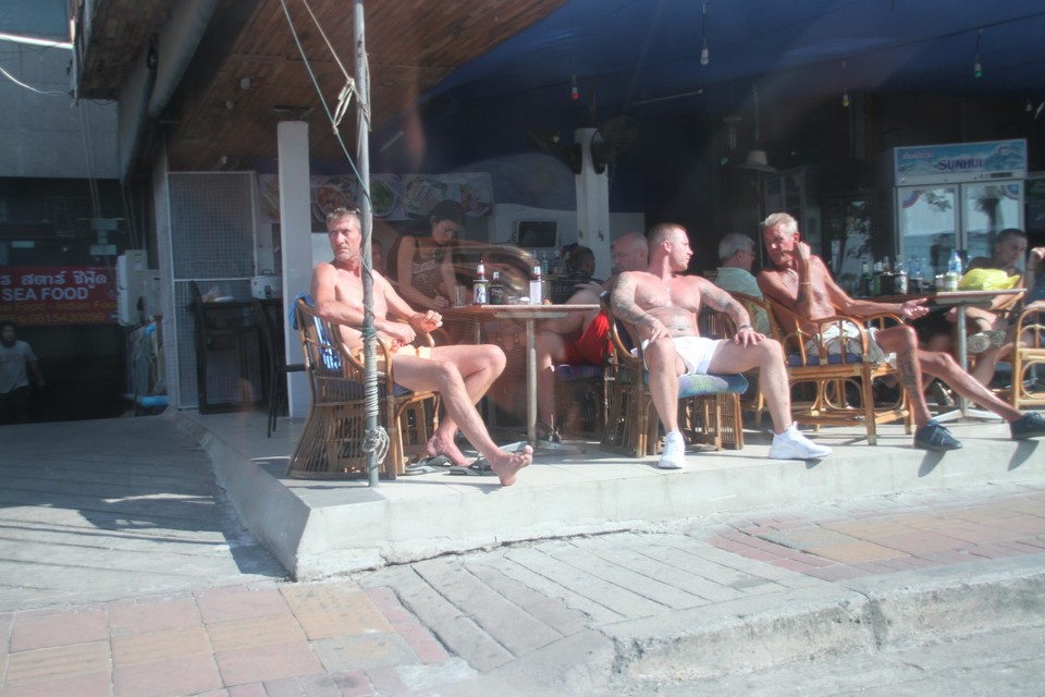 Tourists sunbath and enjoy refreshments opposite the beach because many beach bed operators have ceased their rental business.