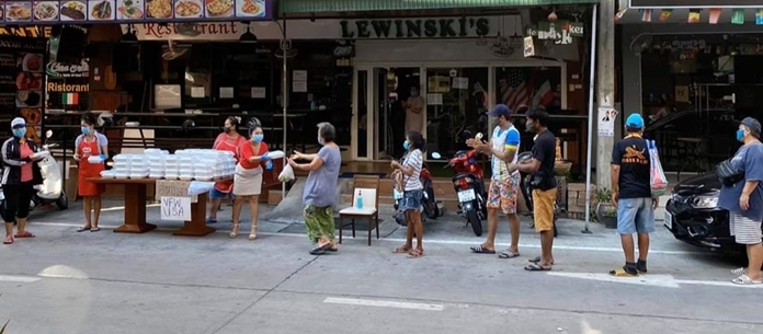 Strict physical distancing is observed as people line up to receive a box of food in front of Lewinski’s Golf Bar & Restaurant.
