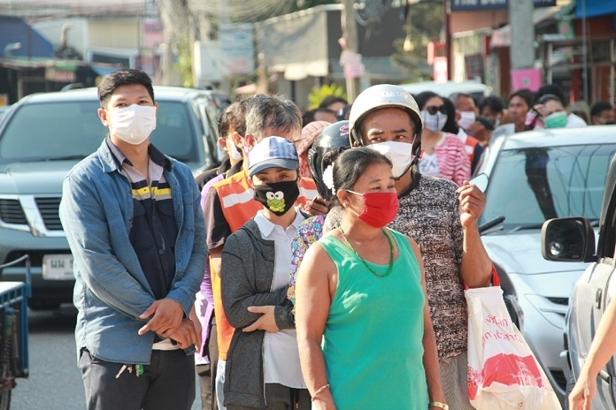 A long line of hungry people wait patiently to be given a box of food.