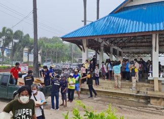Shutdown-ravaged, public stands in rain for food handouts near Pattaya