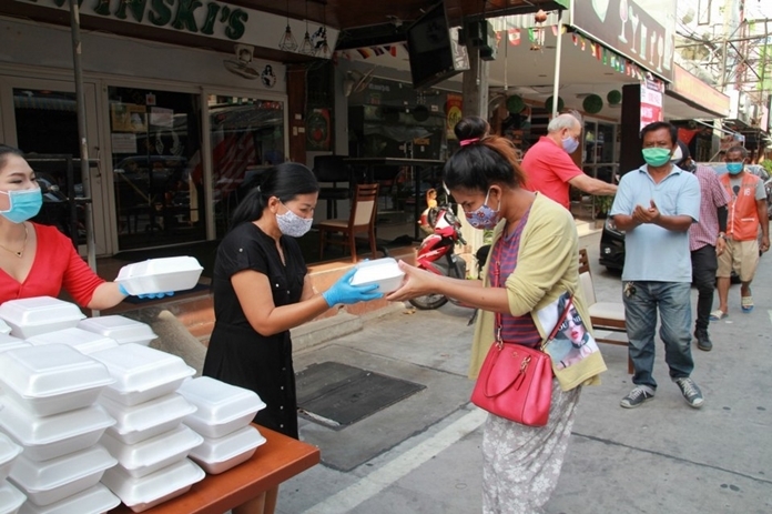 Noi Emerson humbly gives a food box to a lady who bows her head in gratitude.