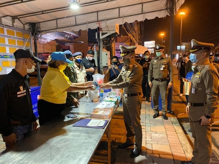 Pol. Lt. Gen. Montree Yimyam hands out hand gel to officers working at the checkpoint.