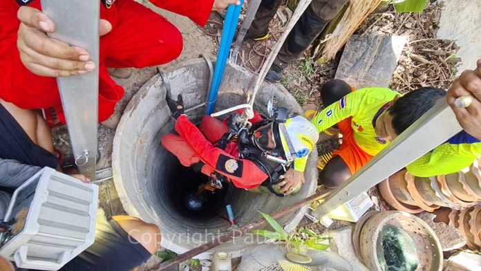 A Sattahip rescue worker is lowered into the well to retrieve the bodies of Nared Pilan and his cousin Komkid Pranut who died of apparent hydrogen sulfide poisoning while dredging a well behind their house.