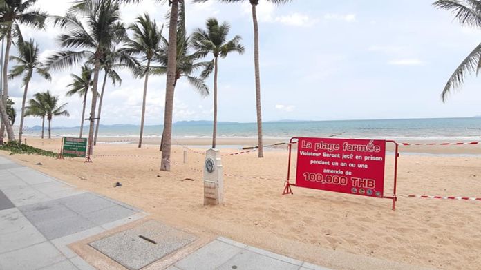 Jomtien beach on a sunny day with signs to warn tourists of the beach closure and punishment for violators.