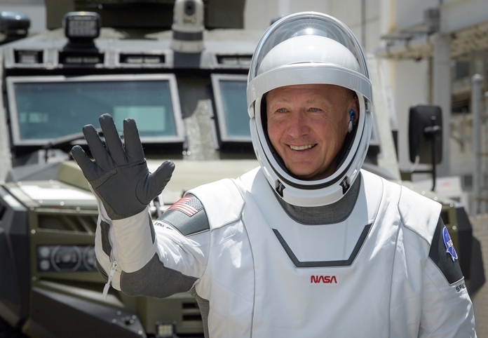 NASA astronaut Douglas Hurley waves as he and fellow crew member Robert Behnken depart the Neil A. Armstrong Operations and Checkout Building for Launch Complex 39A to board the SpaceX Crew Dragon spacecraft for the Demo-2 mission launch, Saturday, May 30, 2020, at NASA’s Kennedy Space Center in Florida.