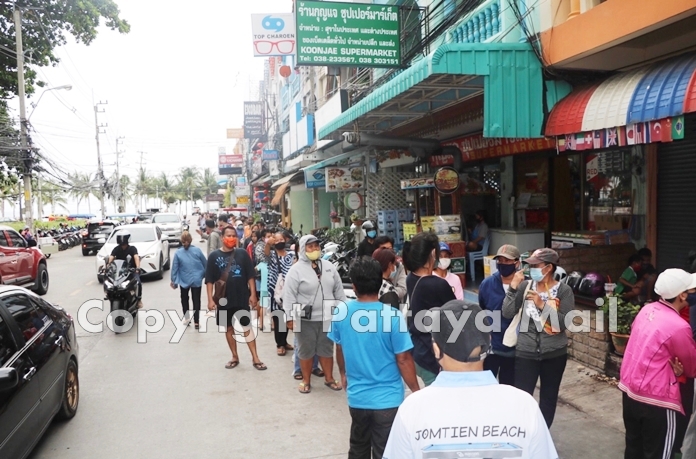 A very long queue of people on Jomtien Beach Road wait for their turn to get care packages.