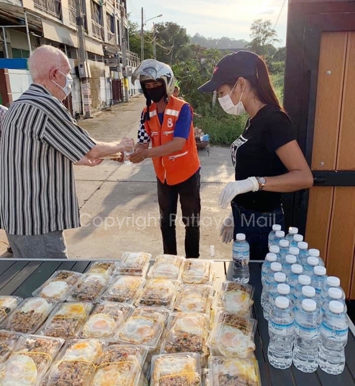 Olivier Gachoud and Chadaporn Petcharachai hand out food and water to a Pattaya resident.