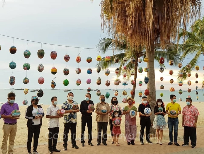 Artists and their work pose for a commemorative photo on the beach.