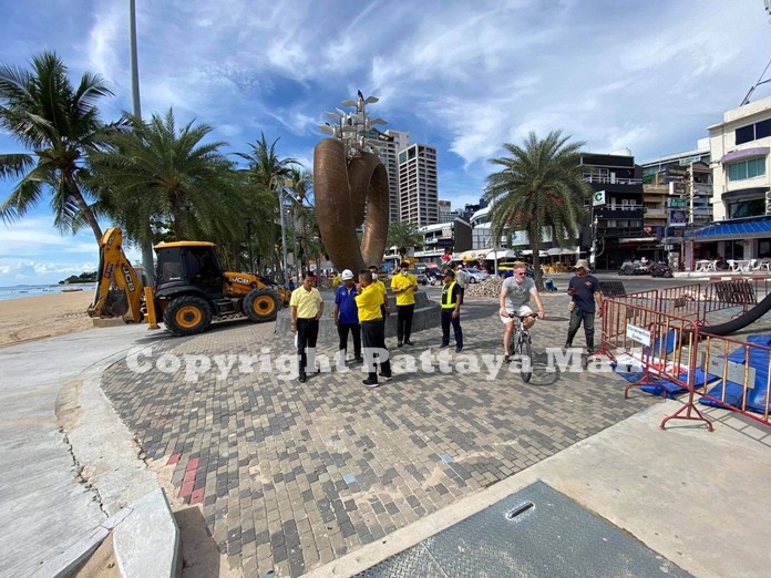 A bicyclist goes on his leisurely ride on the attractive beach promenade while city officials inspect the work in progress.